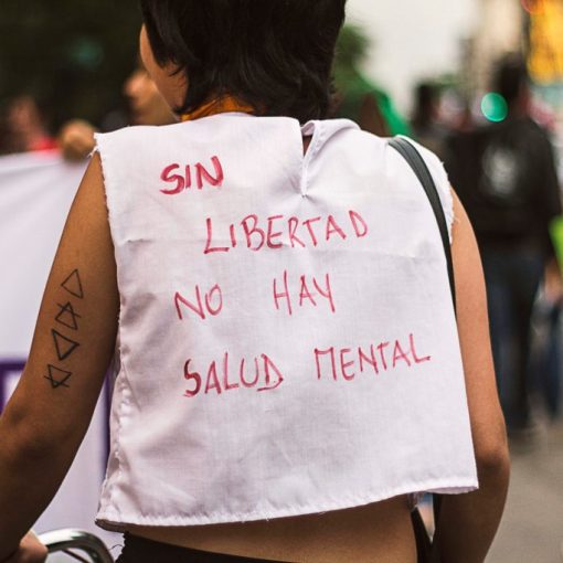 Imagen: en la marcha por el derecho a la salud mental. Se ve a una persona con una pechera que dice "Sin libertad no hay salud mental"