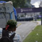 Foto de una mujer de espaldas sosteniendo un cartel en una manifestación. En el cartel se lee: "Fuertes con los débiles". Fuente: tapa del libro.