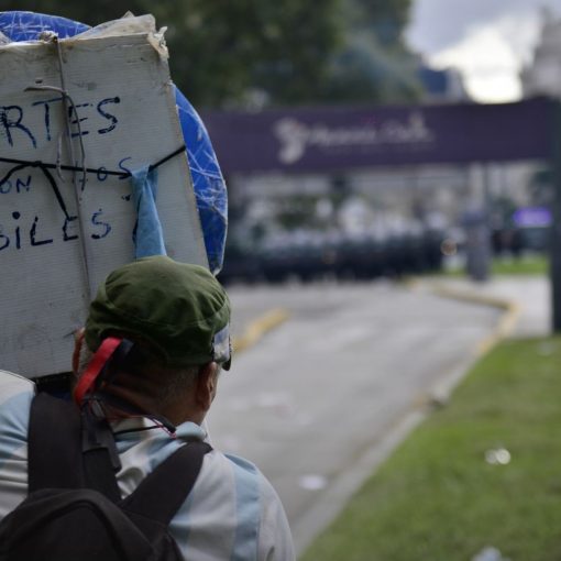 Foto de una mujer de espaldas sosteniendo un cartel en una manifestación. En el cartel se lee: "Fuertes con los débiles". Fuente: tapa del libro.